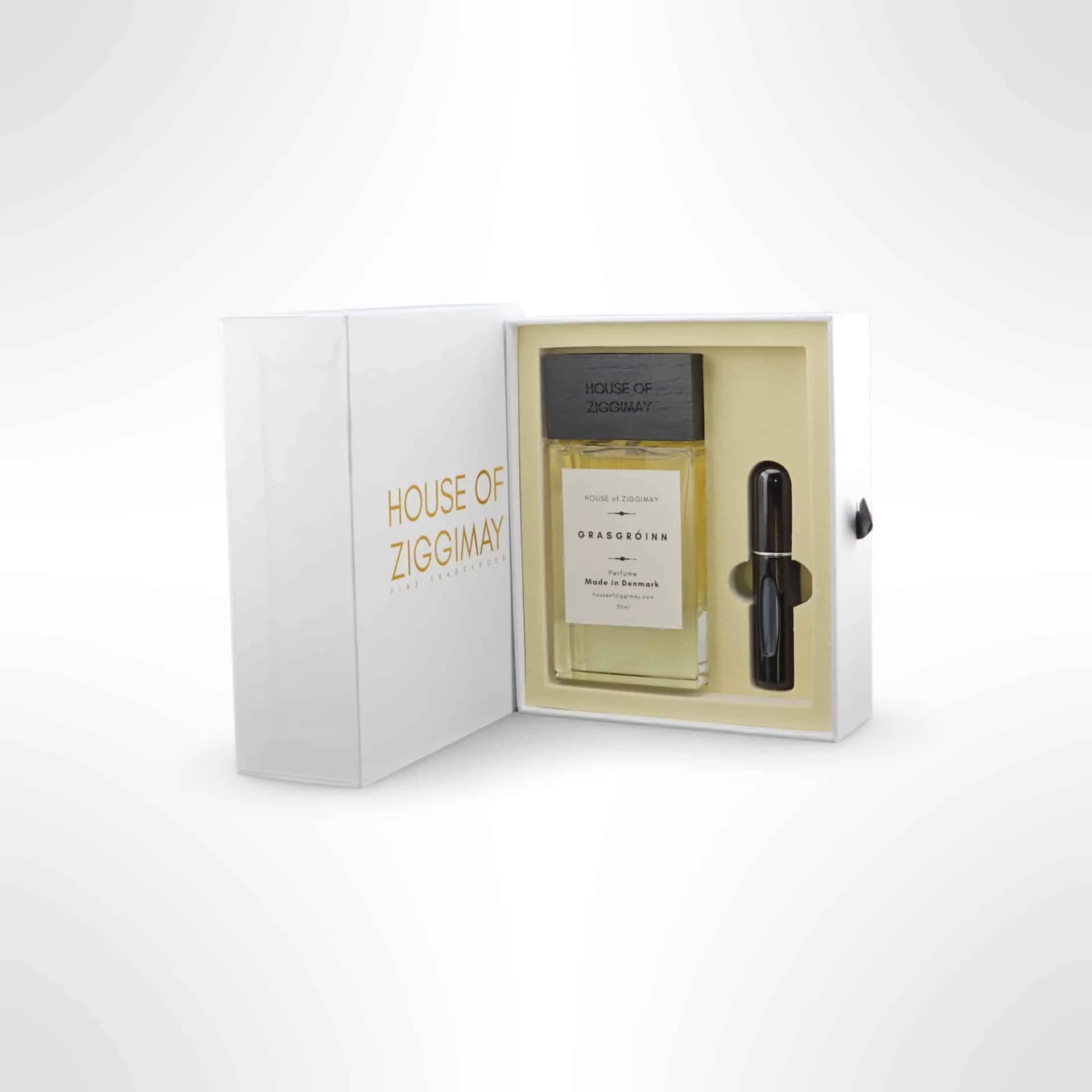 The House of Ziggimay perfume set, featuring the exquisite Grasgróinn fragrance, presents a sleek white and gold box. Inside, a full-sized bottle nestles beside a handy spray vial. This minimalist design embodies elegance and evokes the natural allure reminiscent of Grassgróinn fields.