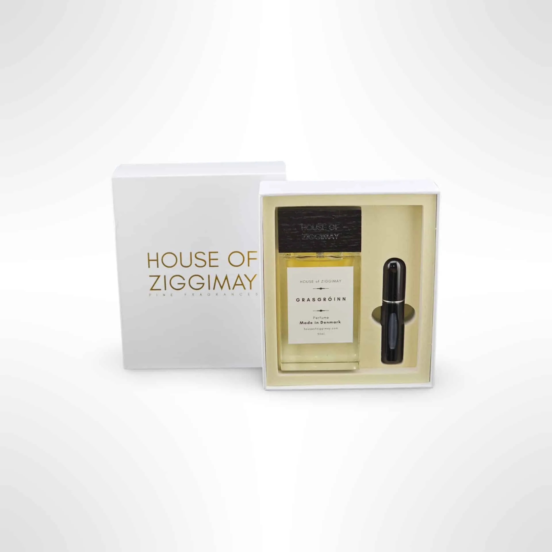 A white box labeled House of Ziggimay contains a bottle of the exquisite fragrance Obaseoishk and a sleek black spray. This charming collection from House of Ziggimay captivates with its unique blend, evoking whispers of Grasgróinn in every spritz.