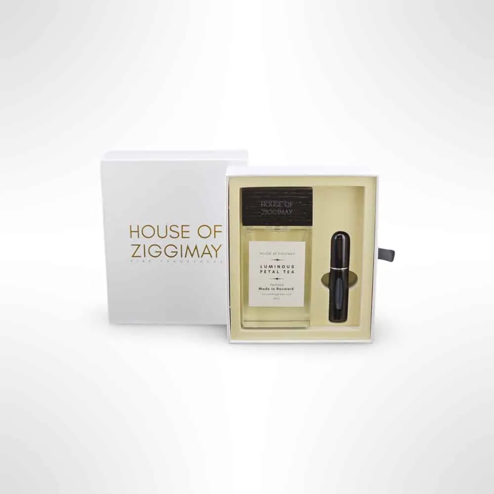 A boxed set of HOUSE OF ZIGGIMAY fragrances. The package contains one large bottle labeled Luminous Petal Tea and a smaller, black cylindrical bottle. This niche perfume set comes in a white box with gold and black text, prominently bearing the elegant HOUSE OF ZIGGIMAY name on the front.