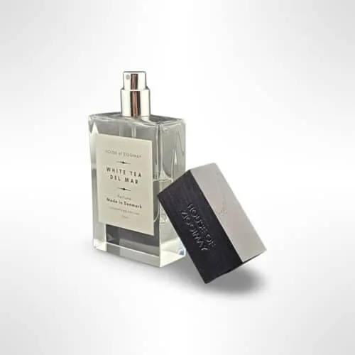 Homepage A variety of elegant perfume bottles in different shapes, sizes, and shades of pink, gold, and clear glass are arranged on tiered white shelves, reflected on a glossy surface perfect for exploring perfume layering or discovering your signature scent.