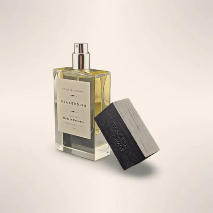 Grasgróinn eau de parfum bottle with its black ash wood cap resting beside it