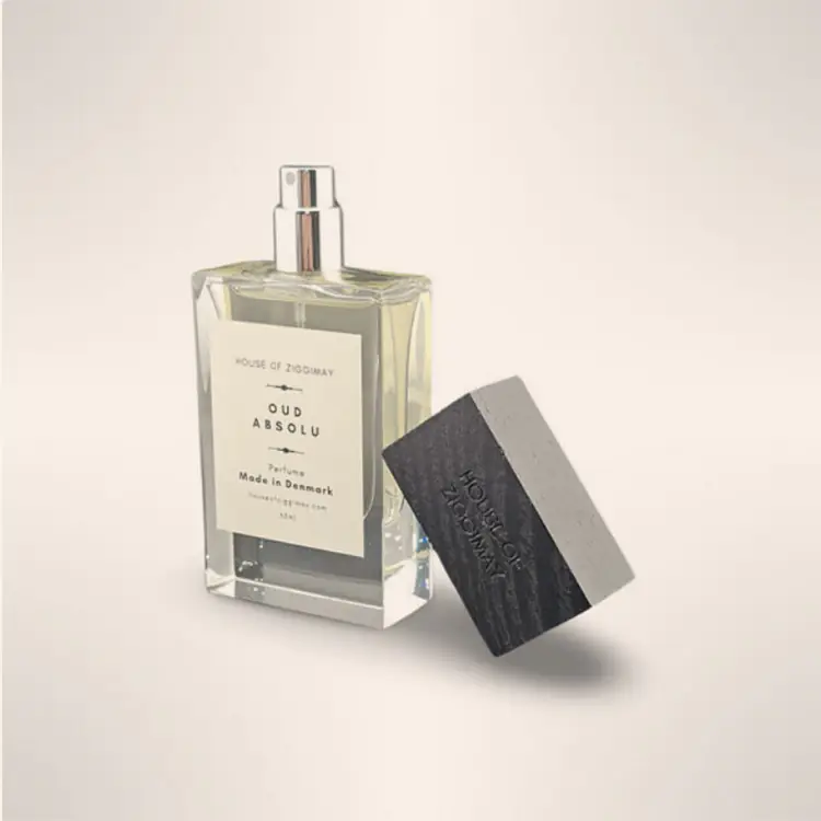 Oud Absolu eau de parfum bottle with its black ash wood cap resting beside it
