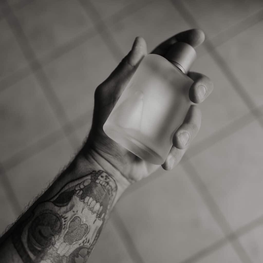 A hand holds a perfume bottle.
